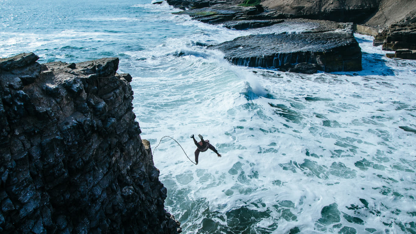 Adventurer cliff jumping into crashing ocean waves