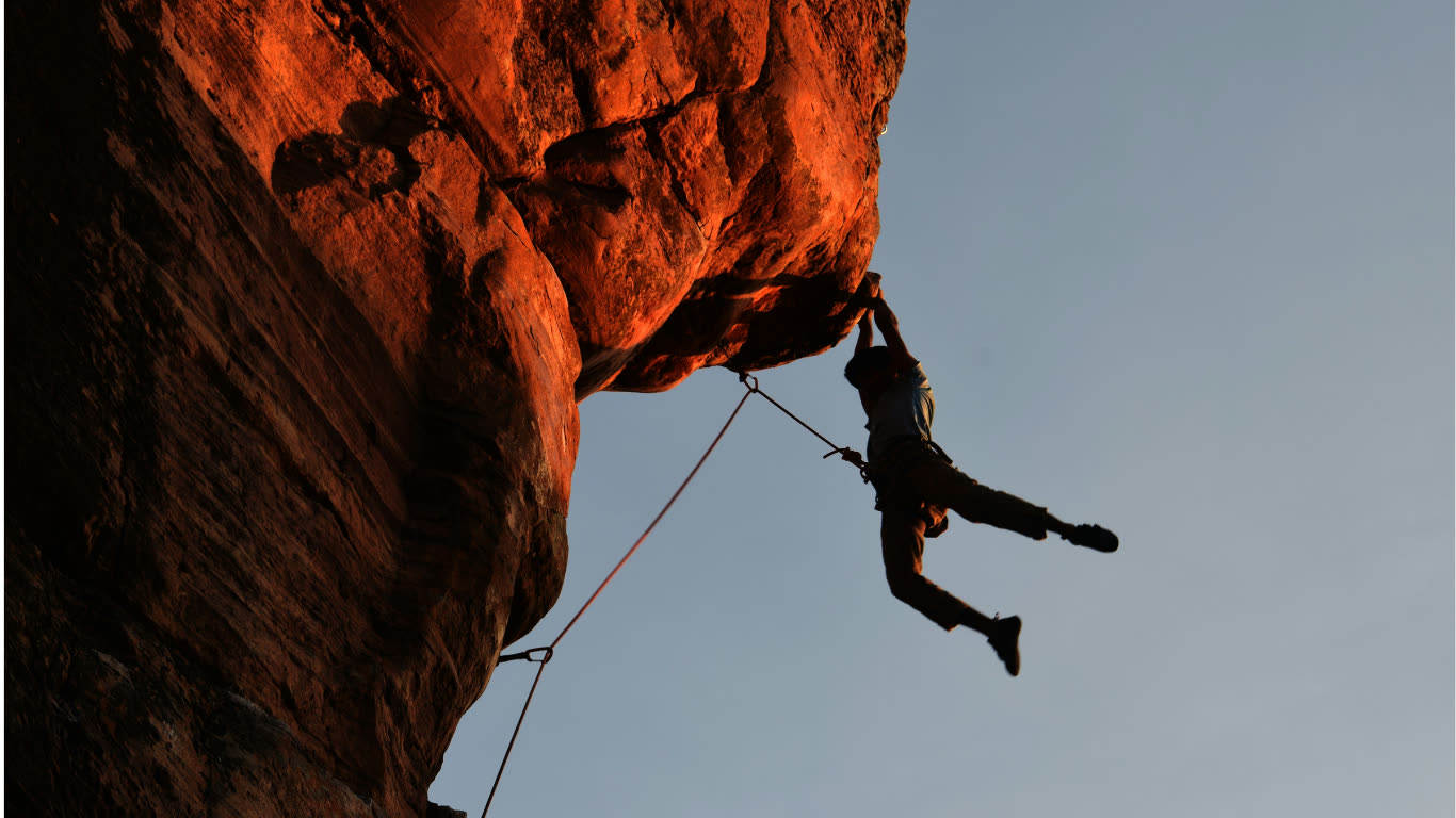 Climber hanging from a sunlit rock overhang